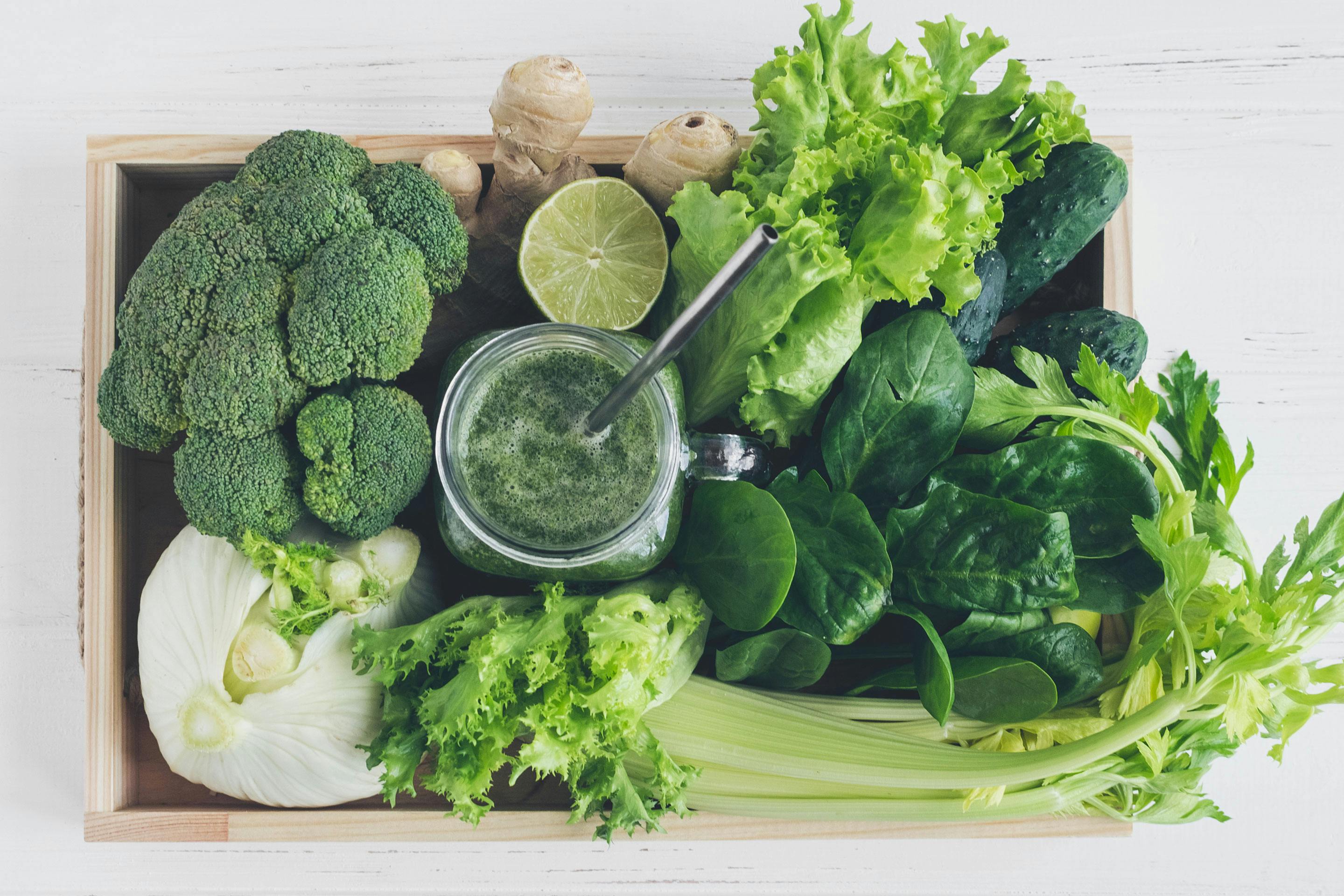 Eine Holzkiste voller grüner Gemüse- und Obstsorten zum Smoothie mixen