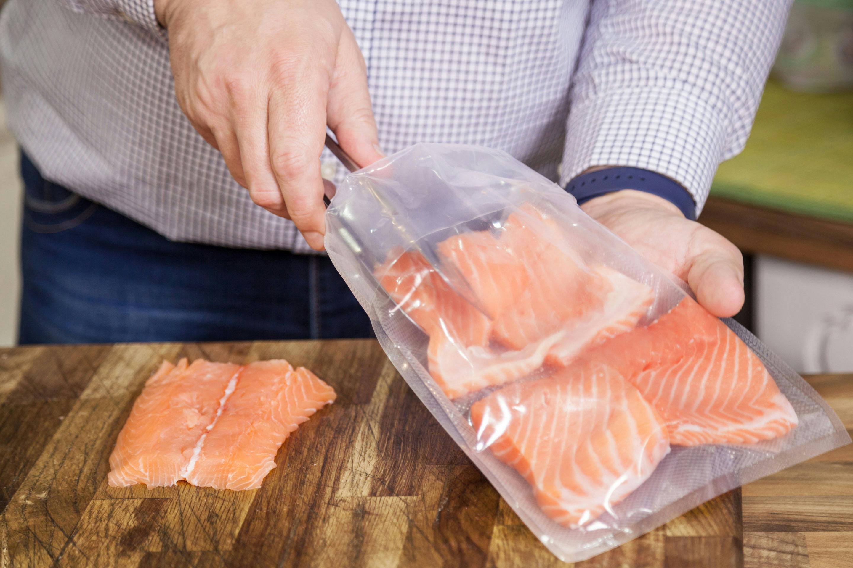 ein Mann gibt Lachsilets in einen BEutel als Vorberitung für Sous vide