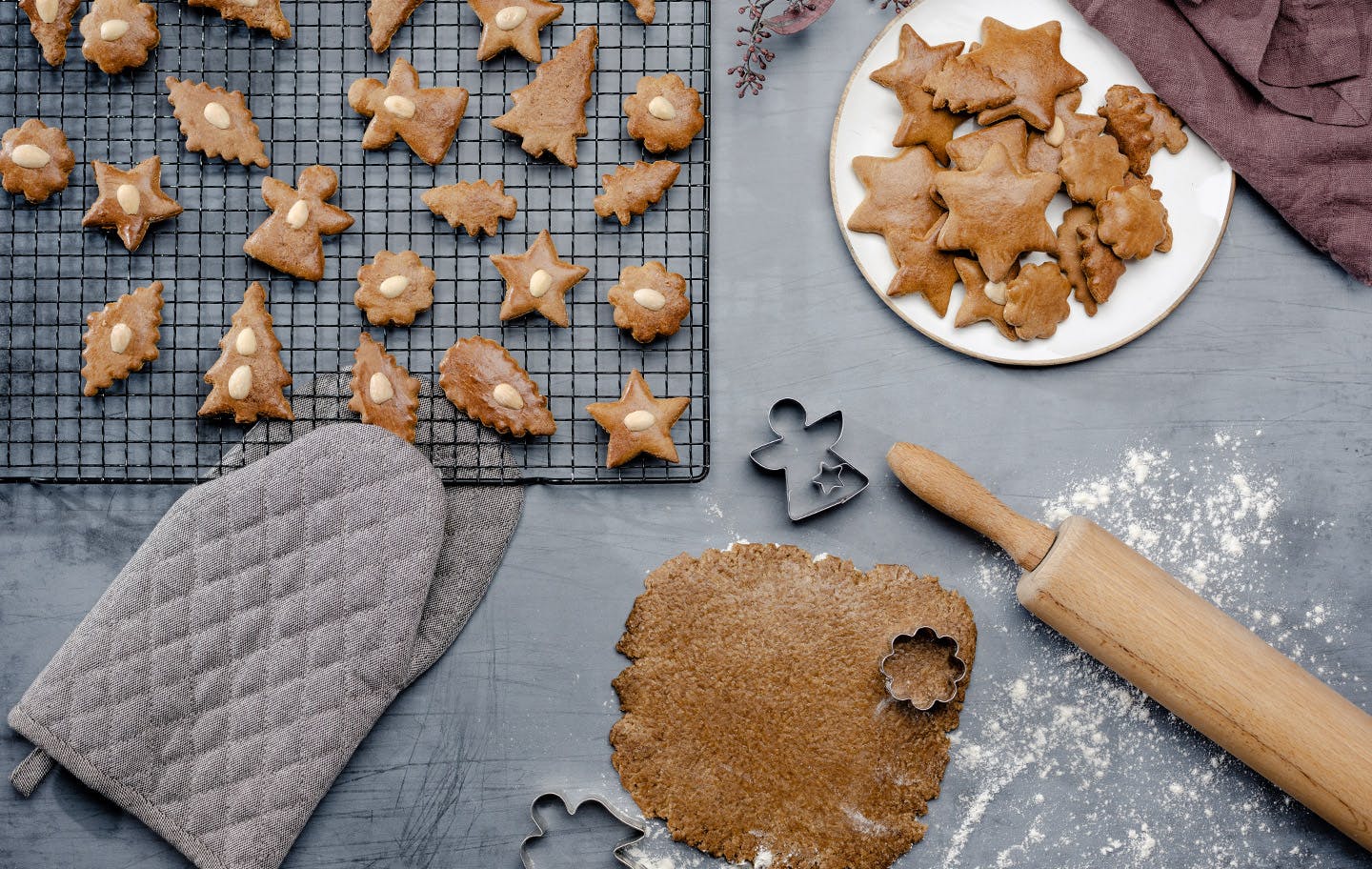 Gebackene Lebkuchen auf einem Kuchengitter und hellem Teller; ausgerollter Lebkuchenteig mit Ausstechern