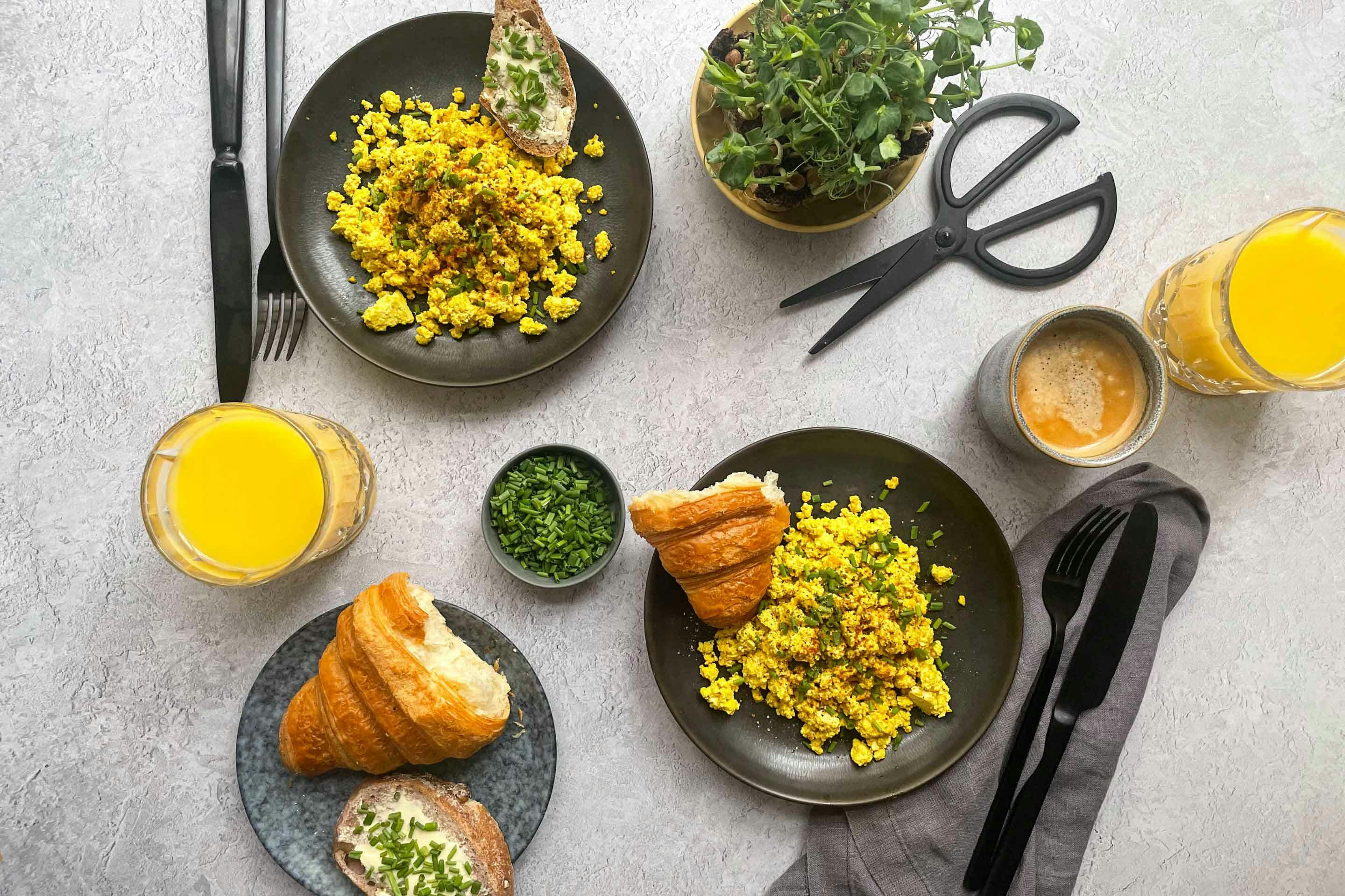 Vegane Tofu-Eierspeise mit Butterbrot und Croissant.