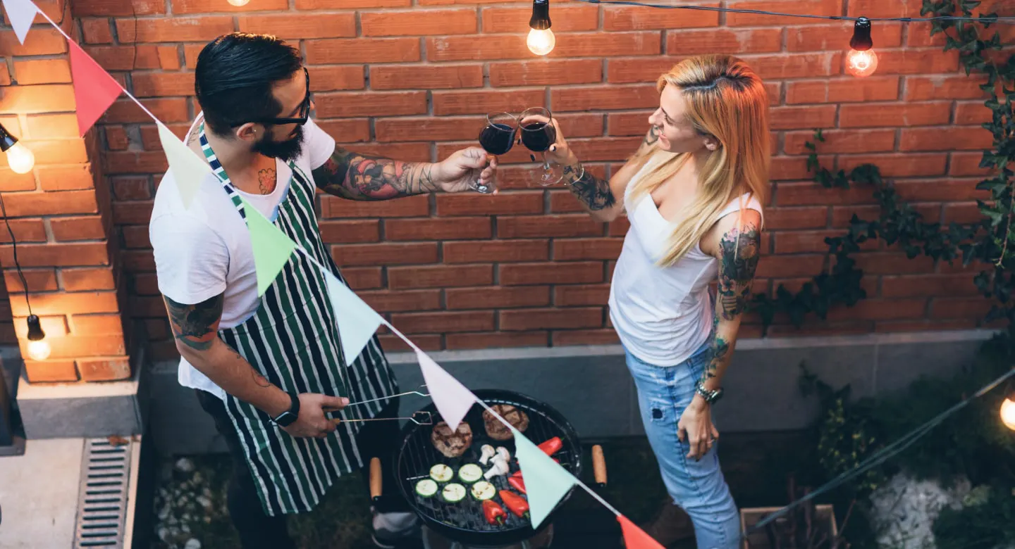 Ein Mann grillt und stoßt mit seinem Date an.